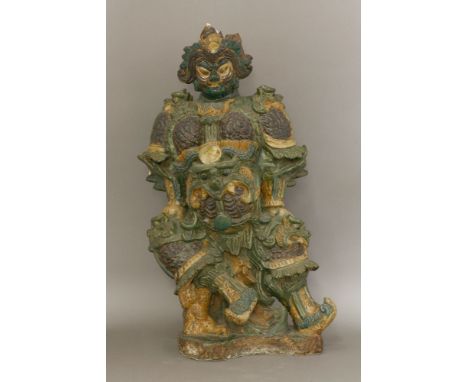 A large earthenware Roof Guardian, probably Ming dynasty, wearing armour, modelled with a devil mask, others at his knees and