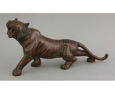 An unusual bronze Tiger, late 19th century, striding forward and roaring, its body patinated copper with black stripes, its e