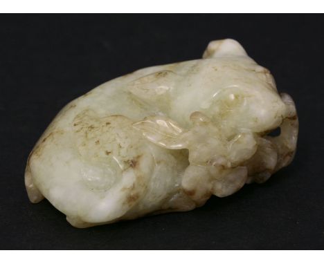 An appealing jade Carving, early 20th century, of a cat recumbent and eating a flowering leaf spray, the stone green-grey and