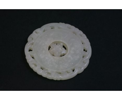 A white jade Disc, probably 18th century, carved as a bi with archaic scrolls, encircling a loose fretwork wheel, the pierced