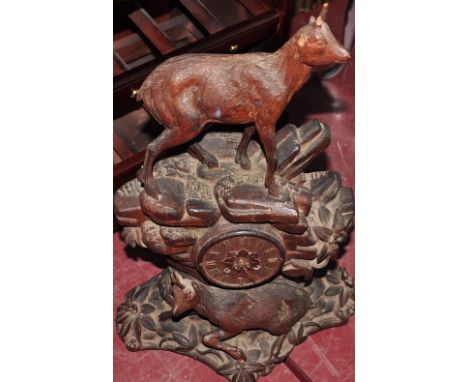 A late 19th Century Black Forest mantel clock carved with deer on a rocky outcrop, h:58cm