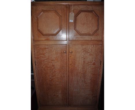 A vintage Heals light oak wardrobe enclosed by two octagonal moulded twin panelled doors, w:106cm