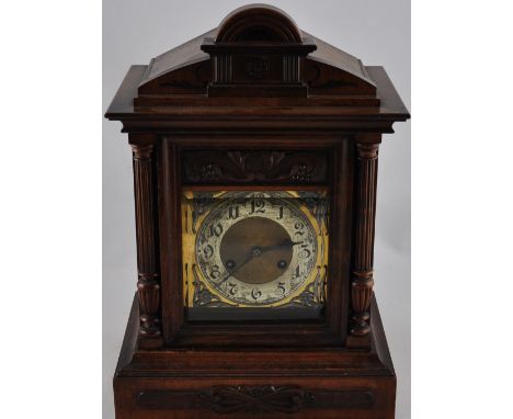 An carved oak cased mantel clock with Arabic numerals on white metal face over polished brass with cast foliate spandrels. Mo