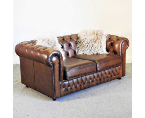 A brown leather upholstered chesterfield sofa, with a button back and loose cushions153w x 90d x 68h cmOverall condition is c