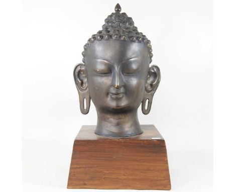 A large bronzed head of a Thai Buddha, mounted on a hardwood stand, 57cm high