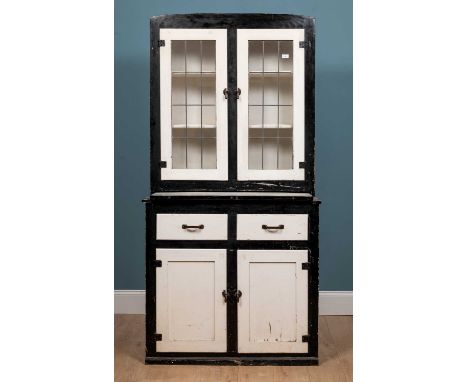 An early 20th century black and white painted kitchen cabinet with leaded glazed doors above an enamel pull-out preparation s