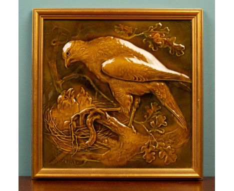 A Burmantoft shallow relief moulded tile decorated with a bird of prey feeding its young, signed 'p. Mallet' and with back st