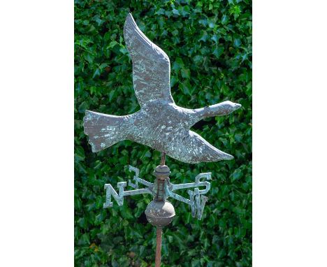 A contemporary weather vane in the form of a flying goose above the cardinal letters and on a wooden baseapproximately 159cm 