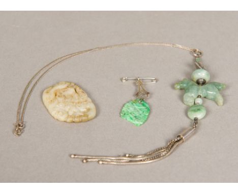 A small Chinese pierced mutton fat jade roundelTogether with a small pierced jade brooch; and a necklace set with a jade hors