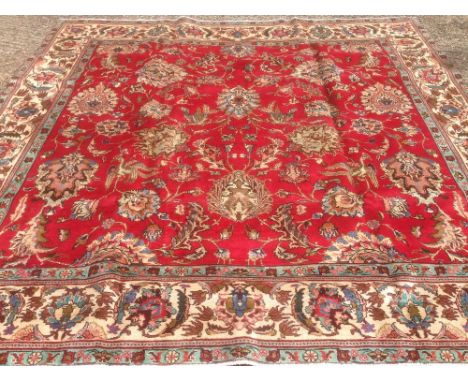 A Tabriz wool carpet The wine red field enclosing flowering acanthus sprays within stylised herati guard stripes and border. 