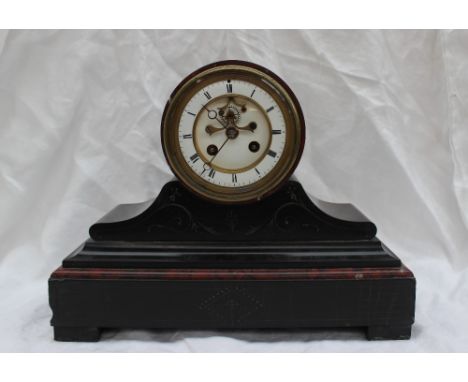 A late Victorian black slate and variegated marble mantle clock, with a white enamel dial and Roman numerals with insight mov