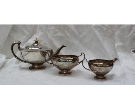 A George V silver three piece teaset, comprising an urn shaped teapot, twin handled sugar basin and cream jug, London, 1919, 