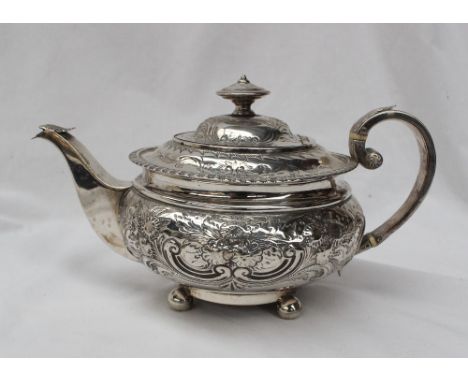 A George IV Scottish silver teapot of squat form embossed with flower heads and leaves on ball feet, Edinburgh, 1818, approxi