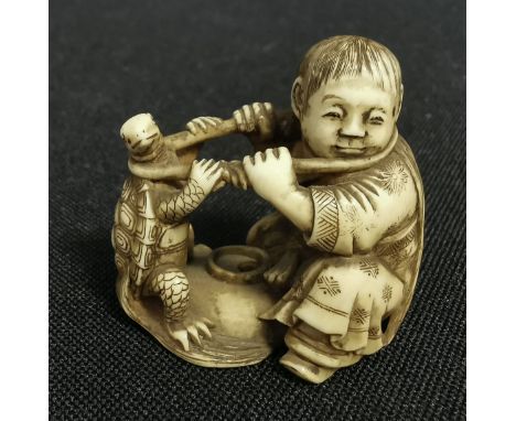 FEINE NETSUKE: KIND MIT SCHILDKRÖTE, Japan, Bein, partiell geschwärzt. Feine, detailreich gearbeitete Netsuke, unter dem Stan