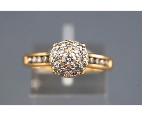 A yellow metal diamond set cluster ring with diamond shoulders. Stamped total diamond weight of 0.72cts. Hallmarked 18ct gold