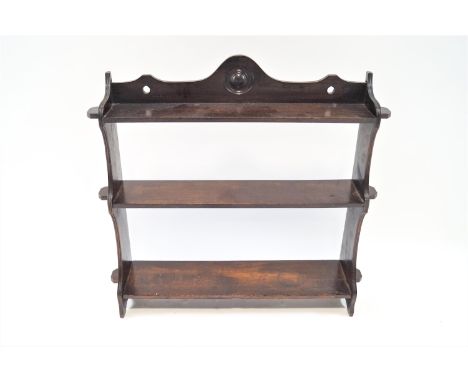 A 19th century oak three tier wall shelf,  with shaped and pierced crest, with cut our sides and peg style protruding ends to