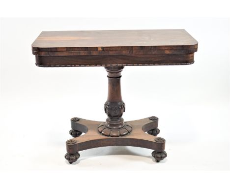 A William IV rosewood card table on turned and carved pedestal with shaped rectangular base on carved feet enclosing casters,