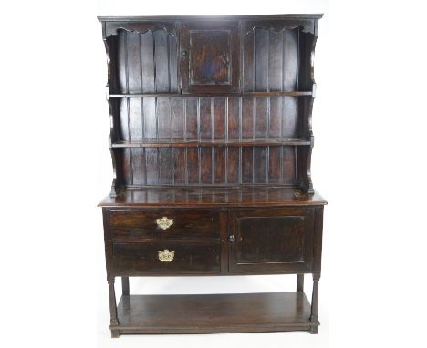 An 18th century oak dresser base with plain rectangular top over a cupboard with a plain panelled door and two drawers raised