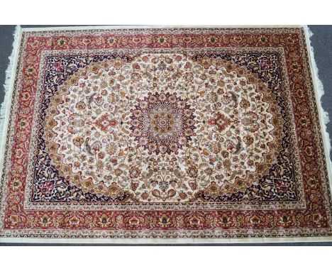 A machine woven Keishan style carpet with central medallion issuing scrolling flowers on a beige ground with blue ground spen