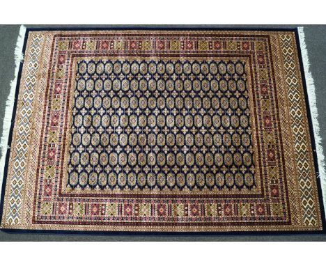 A machine woven Bokhara style carpet with thirteen rows of medallions on a blue ground within multiple borders, 280cm x 200cm