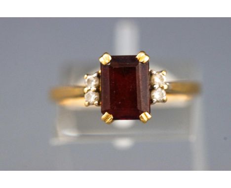 A yellow metal dress ring set with a rectangular cut garnet and four round brilliant cut diamonds. Hallmarked 18ct gold, Shef