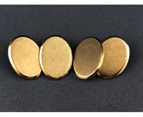 A yellow metal pair of oval chain link cufflinks having a plain and engine turned design. Hallmarked 9ct gold, Birmingham, 19