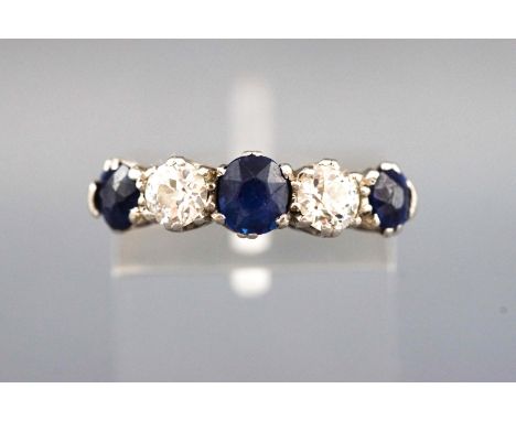 A yellow and white metal half hoop ring set with three round faceted cut sapphires and two old brilliant cut diamonds. Approx