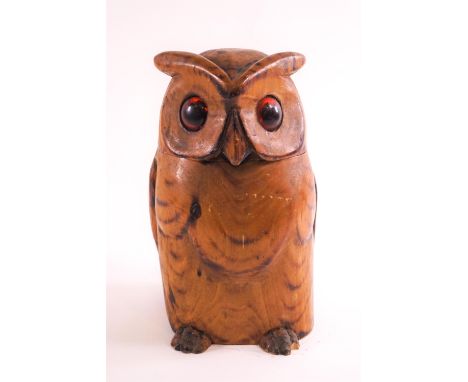 A carved owl tobacco box, in light wood, the hinged head lid set with amber glass eyes, 23cm high