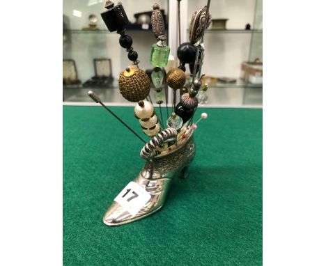 A SHOE FORM PIN CUSHION WITH VARIOUS HAT PINS.
