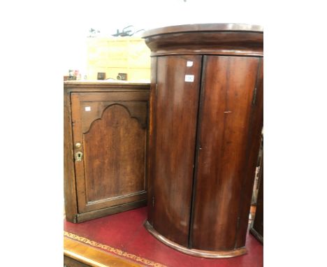 TWO LATE GEORGIAN HANGING CORNER CABINETS, ONE OAK EXAMPLE WITH PANEL DOOR AND A MAHOGANY BOWFRONT EXAMPLE (2)