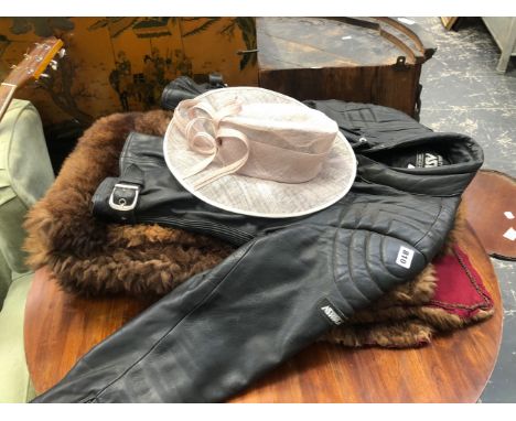 A BLACK LEATHER MOTORBIKE JACKET TOGETHER WITH A FUR RUG AND A LADYS HAT