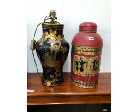 A BLACK GROUND CHINOISERIE BALUSTER TABLE LAMP TOGETHER WITH A RED GROUND TEA CANNISTER INSCRIBED WITH SIMULATED CHINESE WRIT