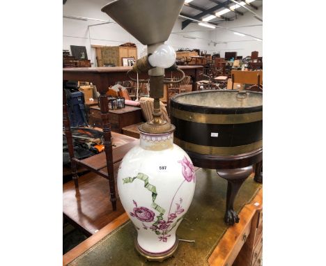 A PORCELAIN BALUSTER VASE AS A TABLE LAMP DECORATED WITH GREEN RIBBON TIED MAUVE FLOWERS