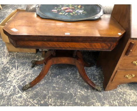 AN INLAID MAHOGANY REGENCY CARD TABLE, SHAPED TOP ABOVE PLATFORM BASE AND SCROLLING LEGS ENDING IN BRASS PAW CASTERS. W 92 D 