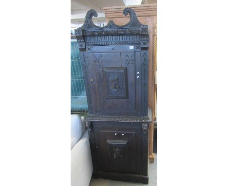 19th Century stained oak two stage blind panelled cupboard with relief portrait panels, under a broken swan neck pediment. (B