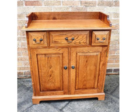 20TH CENTURY OAK CABINET, with a wooden galleried top above a central long drawer, flanked by two short drawers above two cup