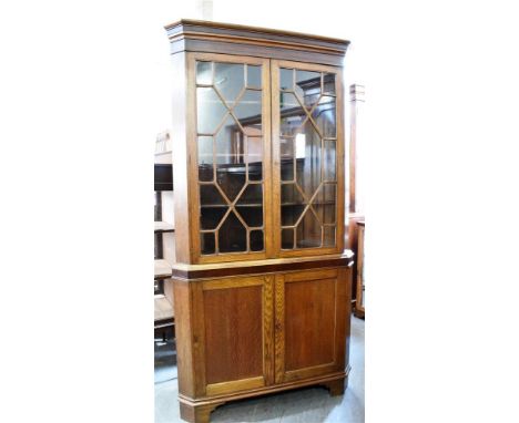 19TH CENTURY OAK FREESTANDING CORNER CABINET, with twin astragal glazed doors above a base of twin cupboard doors, and raised