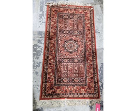 Eastern red ground rug with central floral medallion flanked by geometric pattern with multiple floral borders, 156cm x 84cm&