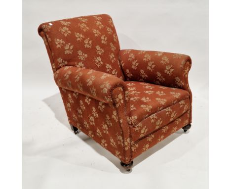 Early 20th century armchair with floral patterned upholstery on a brown ground, on oak bun feet with castors (one castor miss