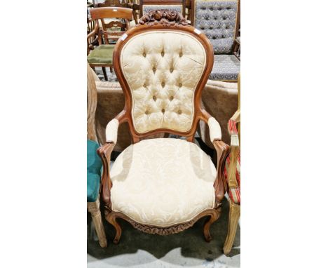 Victorian-style hardwood open armchair, the top rail with floral carved cresting, the gold-coloured upholstery with a foliate