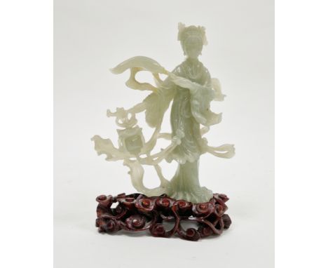 20th century Chinese carved green stone model of a Guanyin, she standing holding a whisk amongst scrolling, pale green tint i