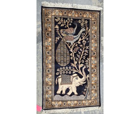 Persian-style midnight ground rug, the central field with elephant and peacocks in tree, multiple floral borders, 128cm x 74c