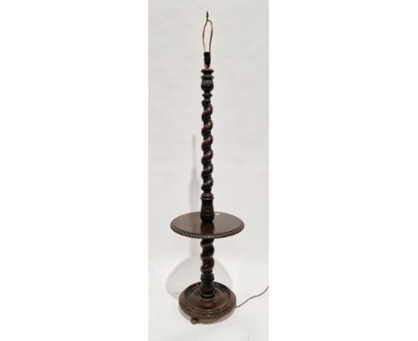 Early 20th century oak standard lamp, the twisted and foliate carved column with an integrated circular wine shelf with flute