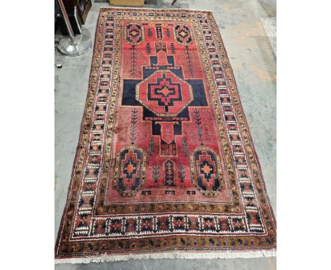 Large Eastern red ground rug&nbsp;with central geometric medallion, four elephant foot guls and multiple geometric borders, 2