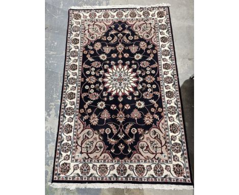 Persian-style midnight ground rug with central floral medallion on floral field with floral spandrels, single herati border a