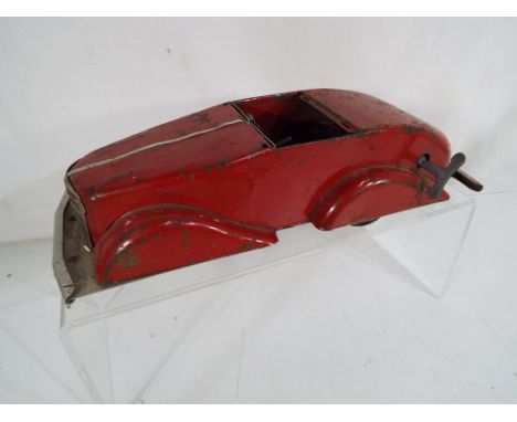 An early tinplate red toy motor car bearing no identification marks, the clockwork mechanism having forward and reverse gears