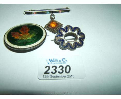 Three silver and enamel brooches and a silver pendant with an orange stone.