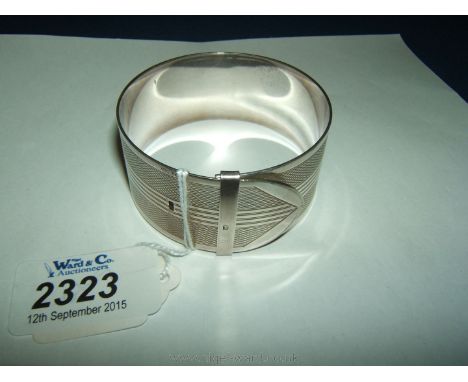 A wide silver belt shaped bangle with engine turned decoration