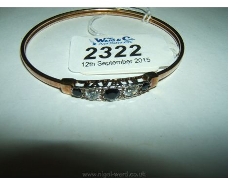 An unmarked gold bangle with three blue and two white stones the setting having the words "Always Forever" either side.