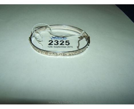 A slim silver bangle with engraved decoration.